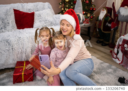 Mother and daughters taking selfie with Christmas presents Mother and daughters taking selfie with Christmas presents 133206740