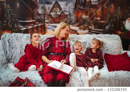 Mother reading holiday book to happy children on cozy sofa Mother reading holiday book to happy children on cozy sofa 133206745