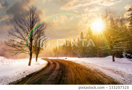 winding road through winter forest at sunset. beautiful nature scenery with naked trees on foggy weather in evening light. transportation background. timeless nostalgia book cover with rainbow 133207328