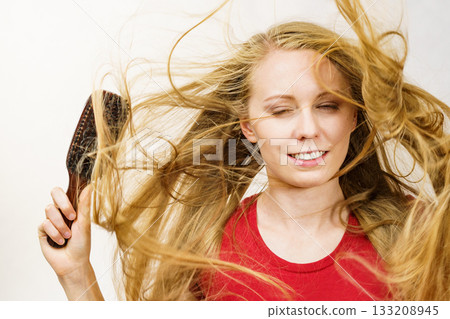 Blonde girl long blowing hair holds natural bristles brush 133208945