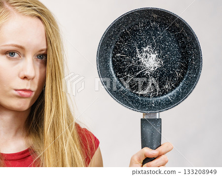 Girl holding scratched frying pan Girl holding scratched frying pan 133208949