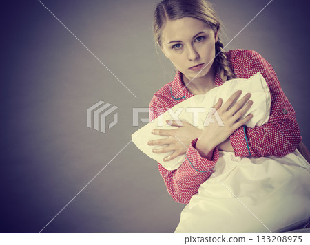 Sad depressed girl in bed gripping pillow Sad depressed girl in bed gripping pillow 133208975