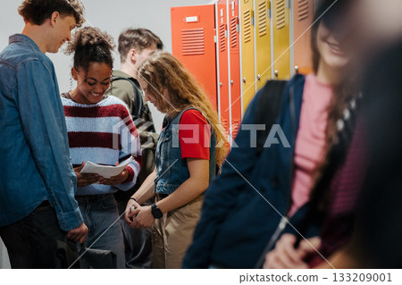 Teen students hanging out in school hallway by lockers. 133209001