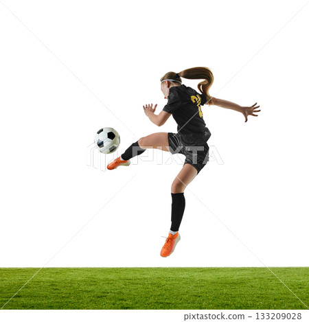 Female football player in powerful mid-air strike with focused intensity Female football player in powerful mid-air strike with focused intensity 133209028
