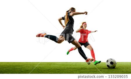 Female football player leaping to shoot ball with determined emotion 133209035