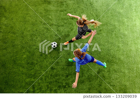 Female soccer players competing for ball in fast offensive clash on grass field Female soccer players competing for ball in fast offensive clash on grass field 133209039