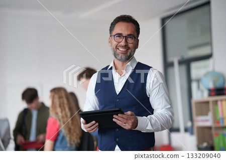 Teacher holding a tablet in modern high school classroom. 133209040