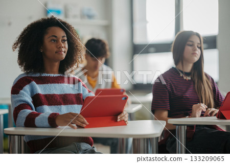 Teen student listening attentively during class with a digital tablet. Teen student listening attentively during class with a digital tablet. 133209065