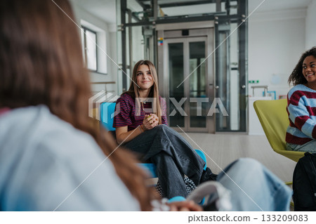 Classmates relaxing and talking in high school lounge. 133209083