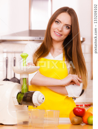 Woman in kitchen preparing fruits for juicing Woman in kitchen preparing fruits for juicing 133209102