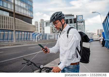 Manager on bike, reading text message on phone. 133209148
