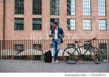City commuter riding bike from work, reading text message on phone. 133209157