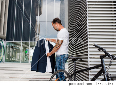 Man preparing for work after cycling, holding business suit. 133209163