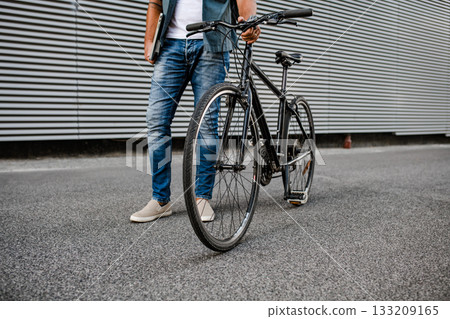 Man riding bike to work in city with helmet and backpack 133209165