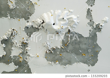 Peeling paint reveals textured layers on a wall in an abandoned building during daylight hours 133209203