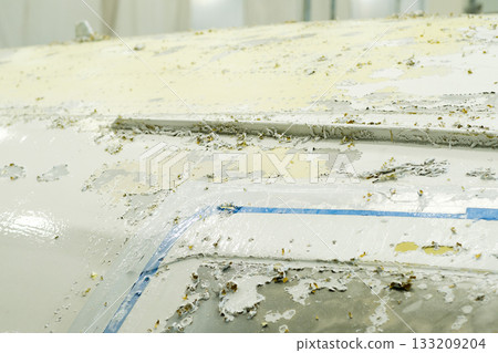 Surface of an aircraft revealing layers of paint and wear at an aircraft maintenance facility during restoration work Surface of an aircraft revealing layers of paint and wear at an aircraft maintenance facility during restoration work 133209204