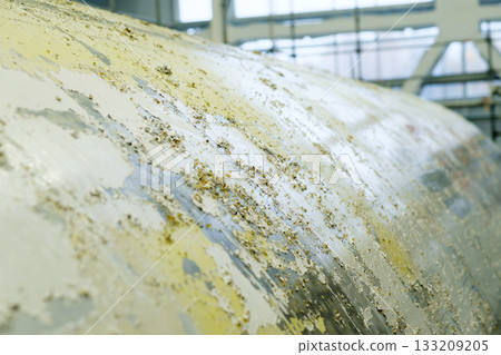Rust accumulation on a large metal surface in an industrial facility during daytime 133209205