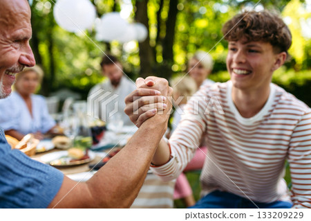 Grandson greeting his grandfather during garden party. 133209229