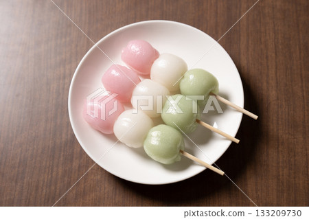 Three tricolored dumplings on a white plate and tea 133209730