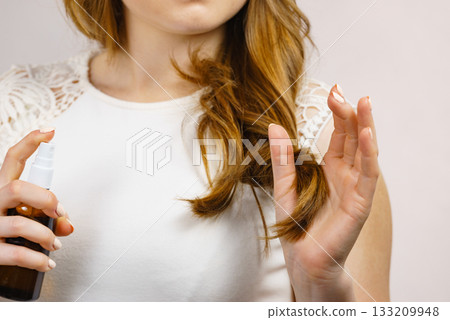 Woman applying hair cosmetic Woman applying hair cosmetic 133209948
