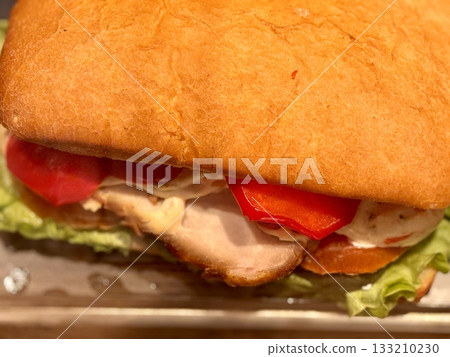 A mouthwatering turkey sandwich featuring fresh lettuce, tomatoes, and flavorful mayo on a toasted roll. Close-up. A mouthwatering turkey sandwich featuring fresh lettuce, tomatoes, and flavorful mayo on a toasted roll. Close-up. 133210230