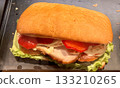A mouthwatering turkey sandwich featuring fresh lettuce, tomatoes, and flavorful mayo on a toasted roll. Close-up. 133210265
