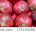 A lot of ripe red pomegranates in a basket on a market counter for sale on sale in vegetable stand display at supermarket show organic food, vegetarian food, healthy food. Close-up. 133210268