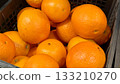 Ripe fresh organic oranges in box on the shelf of a fruit supermarket are displayed for sale. Close-up 133210270