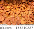 Lots of delicious plump golden orange dried apricots piled up on a tray for sale in a supermarket. Close-up. 133210287