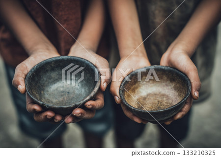 A close-up of children's hands holding empty bowls, symbolizing severe food scarcity and the heartbreaking reality of hunger. A close-up of children's hands holding empty bowls, symbolizing severe food scarcity and the heartbreaking reality of hunger. 133210325