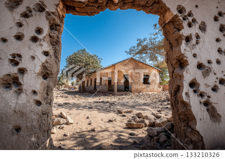 A school building riddled with bullet holes, yet still standing, representing the impact of conflict on education and future. A school building riddled with bullet holes, yet still standing, representing the impact of conflict on education and future. 133210326
