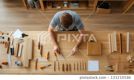 Overhead view of a woodworker organizing tools on a wooden workbench 133210586