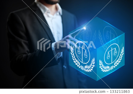 Business professional interacting with digital legal symbol in modern office setting Business professional interacting with digital legal symbol in modern office setting 133211863