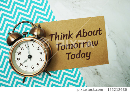 Think about Tomorrow Today text written on paper card with alarm clock on marble background 133212686