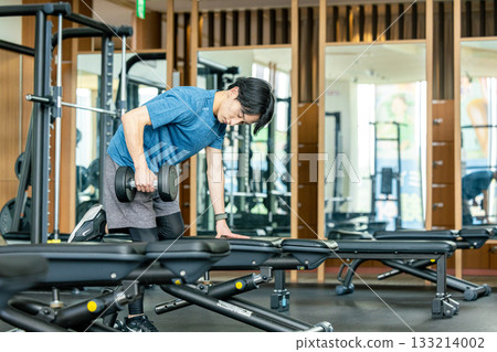A young man doing muscle training with dumbbells at a training gym 133214002