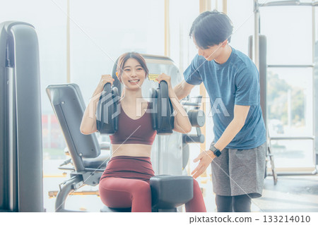 A woman doing strength training at the gym with an instructor 133214010