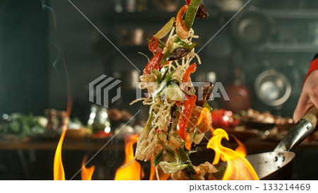 Freeze Motion of Flying Asian Meal with Vegetable and Prawns into Wok Pan 133214469