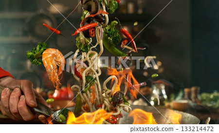 Freeze Motion of Flying Asian Meal with Vegetable and Prawns into Wok Pan 133214472