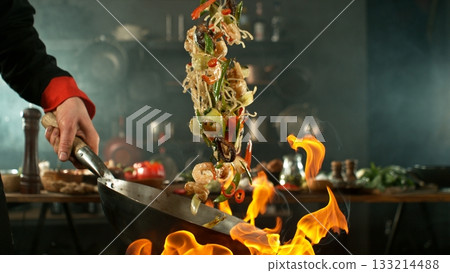 Freeze Motion of Flying Asian Meal with Vegetable and Prawns into Wok Pan 133214488