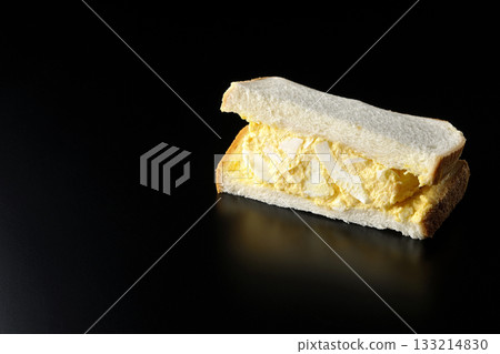 Egg sandwich photographed alone against a black background 133214830