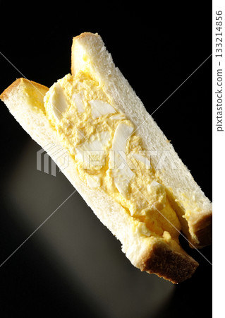 Egg sandwich photographed alone against a black background 133214856