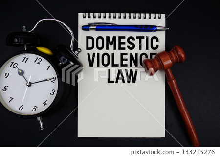 Domestic Violence Law text written on notepad with gavel and alarm clock on black background 133215276