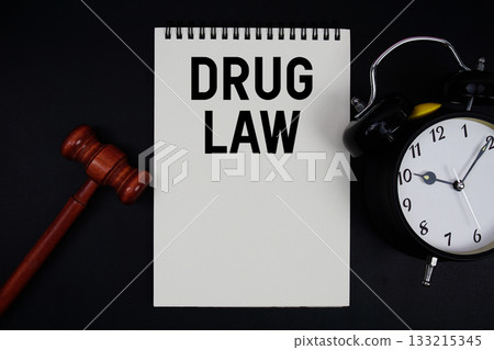 Drug Law text written on notepad with gavel and alarm clock on black background Drug Law text written on notepad with gavel and alarm clock on black background 133215345