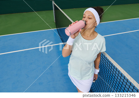 Athletic Woman Drinking Pink Smoothie On Tennis Court During Practice Athletic Woman Drinking Pink Smoothie On Tennis Court During Practice 133215346