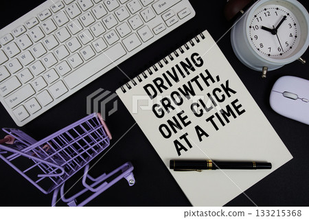 Driving Growth, One Click at a Time text written on notepad with keyboard and trolley shopping cart on black background 133215368