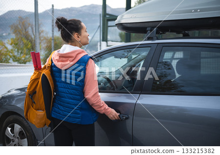 Woman With Backpack Opens Car Door For Road Trip With Roof Box On SUV Woman With Backpack Opens Car Door For Road Trip With Roof Box On SUV 133215382