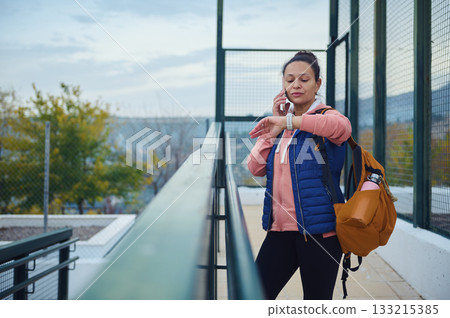 Busy Woman On Phone Checks Time With Backpack On Urban Bridge 133215385