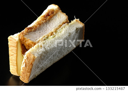 Thick-cut pork cutlet sandwich photographed alone against a black background Thick-cut pork cutlet sandwich photographed alone against a black background 133215487