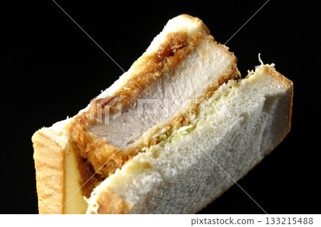 Thick-cut pork cutlet sandwich photographed alone against a black background Thick-cut pork cutlet sandwich photographed alone against a black background 133215488