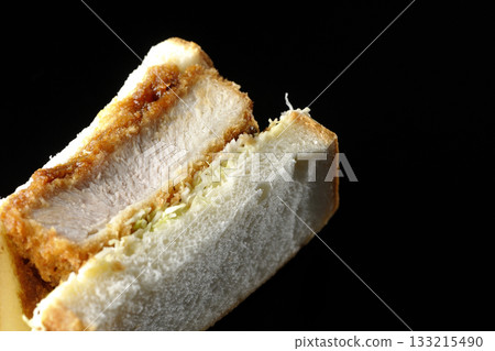 Thick-cut pork cutlet sandwich photographed alone against a black background 133215490